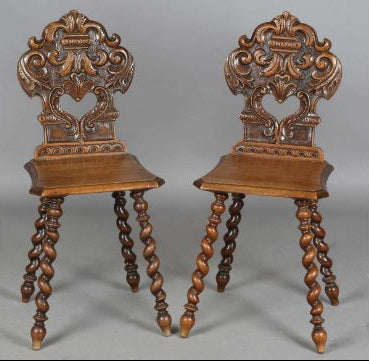 A pair of late 19th century French walnut hall chairs with carved foliate backs above solid panel